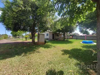 Vista externa de um terreno com gramado e árvores ao redor de uma residência.