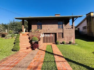 Fachada de casa de tijolos com jardim e calçada de tijolos vermelhos.