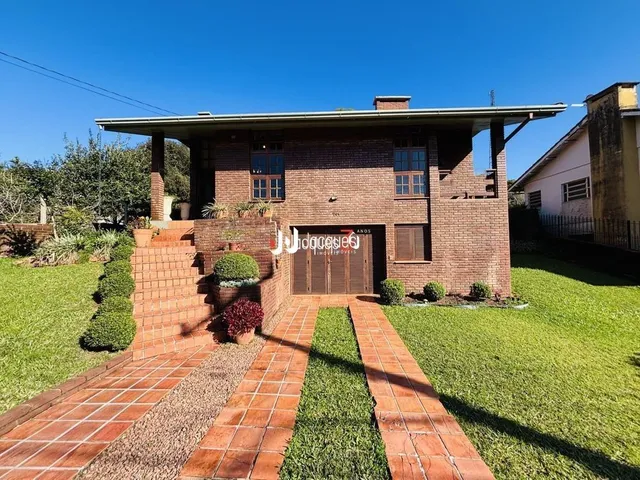 Fachada de casa de tijolos com jardim e calçada de tijolos vermelhos.