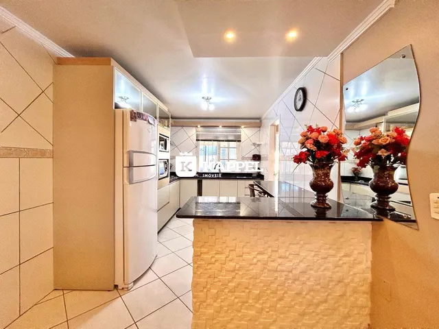 Cozinha com armários brancos e bancada escura.