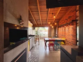 Ambiente interno de uma sala de jantar e cozinha com teto de madeira e parede de tijolos aparentes.