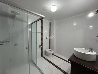 Foto de um banheiro com box de vidro e revestimento cerâmico.