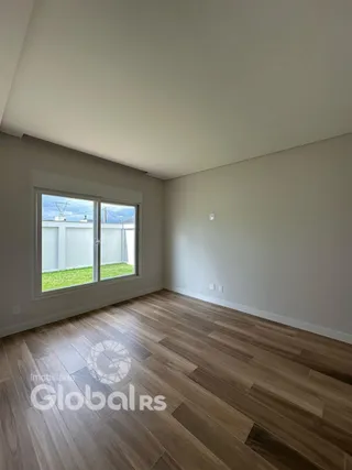 Vista interna de uma sala com piso de madeira e janela.