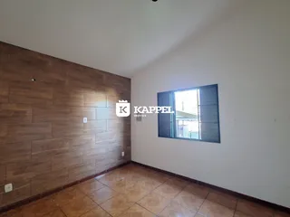 Foto interna de uma sala com piso de cerâmica e painel de madeira na parede.
