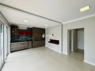Ambiente interno de sala de estar e cozinha com piso claro.