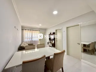 Vista de uma sala de jantar com mesa branca e cadeiras em um imóvel.