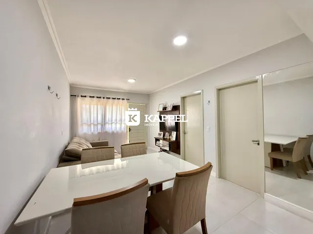 Vista de uma sala de jantar com mesa branca e cadeiras em um imóvel.