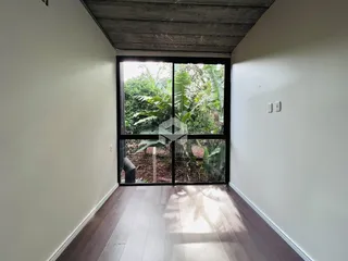Vista interna de um ambiente com piso de madeira e grande janela.