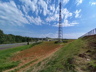 Paisagem externa mostrando uma estrada e uma torre de transmissão sob um céu azul.