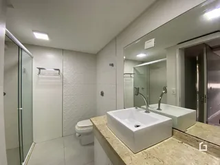 Foto de um banheiro com box de vidro e bancada de granito.