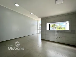 Ambiente interno de uma sala ampla com piso de cerâmica e grande janela.