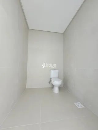 Foto de um banheiro com revestimento cerâmico branco e vaso sanitário.