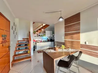 Interior de uma sala de jantar com decoração moderna e escadaria de madeira.