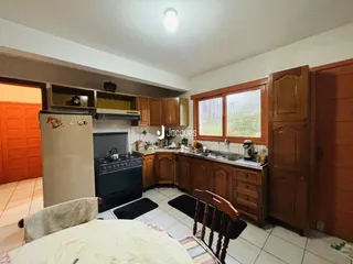 Interior de uma cozinha com armários de madeira e janela no Brasil.