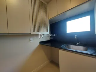 Vista interna de uma cozinha com armários e bancada escura.