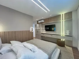 Quarto com cabeceira de madeira e televisão montada na parede.