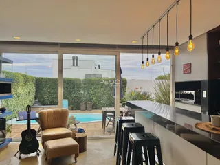 Sala de estar com vista para piscina e jardim através de portas de vidro.