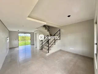 Sala ampla com piso de porcelanato e escadaria visível.