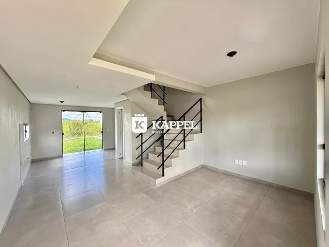 Sala ampla com piso de porcelanato e escadaria visível.