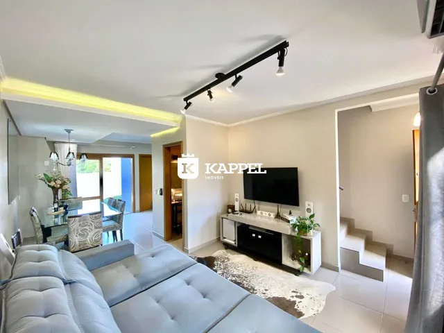 Sala de estar moderna com sofá grande e televisão montada na parede.