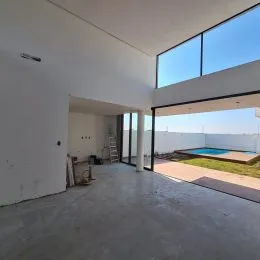 Vista interna de um espaço com grandes aberturas para o exterior.