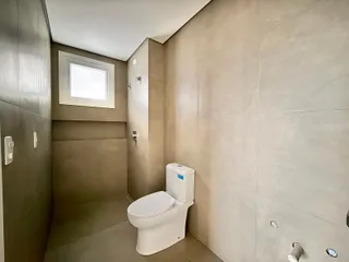 Foto de um banheiro com revestimento de azulejos claros e vaso sanitário branco.