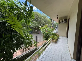 Vista externa de um pátio com piso de cerâmica e vegetação.