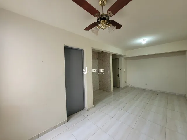 Uma sala de estar com piso de cerâmica clara e paredes brancas.