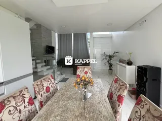 Sala de estar com mesa de madeira e poltronas decoradas em um ambiente claro.
