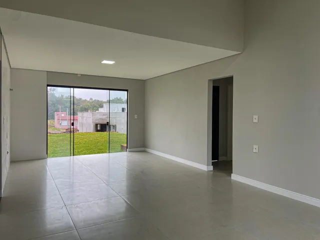 Ambiente amplo com piso de concreto e porta de vidro que dá acesso a um gramado externo.