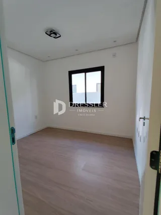 Ambiente interno de uma sala com piso de madeira clara e janela.