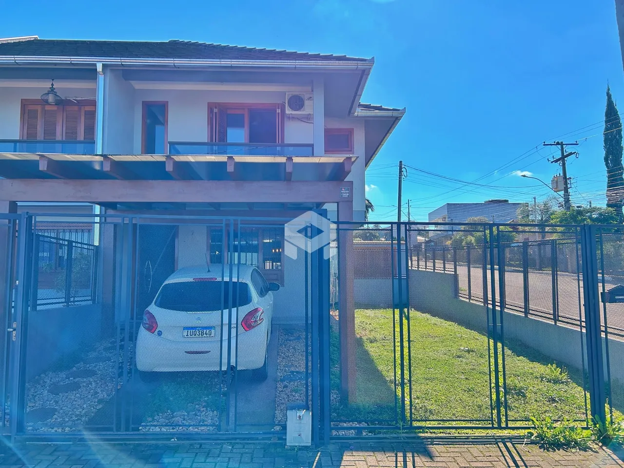 Fachada de uma casa em Lajeado, Brasil, com portão de ferro e gramado.