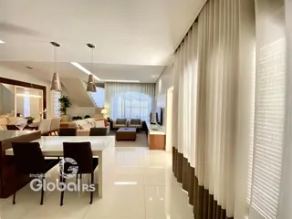 Sala de estar ampla com piso claro e cortinas longas.