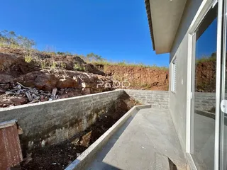 Vista da fachada de uma propriedade com um talude de terra e muro de contenção.