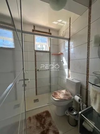 Foto de um banheiro interno com revestimento branco e piso claro.