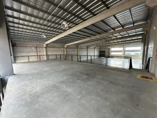 Espaço industrial amplo com teto de metal e piso de concreto.