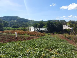 Vista externa de uma propriedade rural com colinas verdes ao fundo.