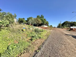 A paisagem exterior da propriedade mostra uma estrada de terra e vegetação densa ao longo da divisa.