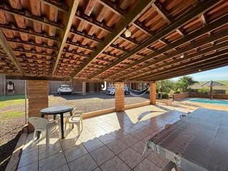 Vista de uma área externa coberta com piso de cerâmica e móveis de jardim.
