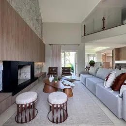 Sala de estar com lareira e painel de madeira na residência.
