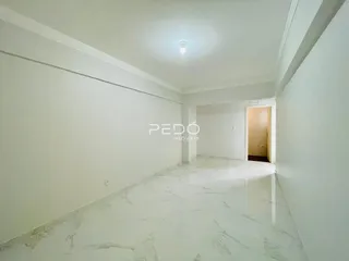 Interior de um ambiente longo com piso de mármore claro.