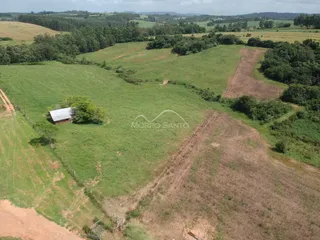 Vista aérea de uma propriedade rural com campos verdes e vegetação.
