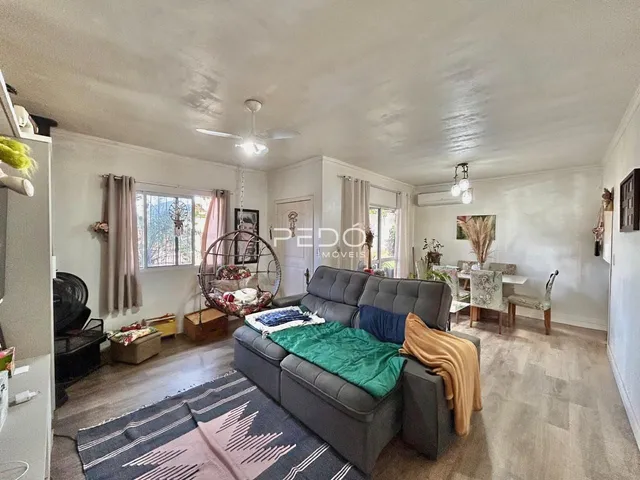 Sala de estar com sofá cinza e piso claro em imóvel no Brasil.
