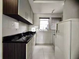 Cozinha com armários escuros e bancada preta em ambiente claro.