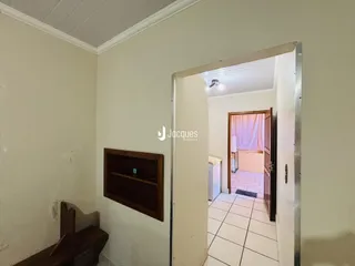 Vista de um corredor interno com uma porta aberta em uma residência.