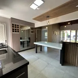 Sala de estar com piso claro e painel de madeira, mostrando uma área interna bem iluminada.