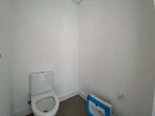 Foto de um banheiro com vaso sanitário branco e paredes brancas.