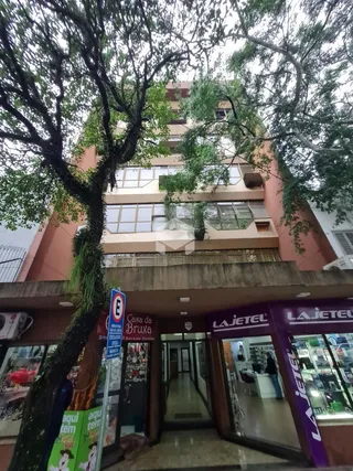 Fachada de um prédio residencial em Lajeado, Brasil, com árvores em primeiro plano.