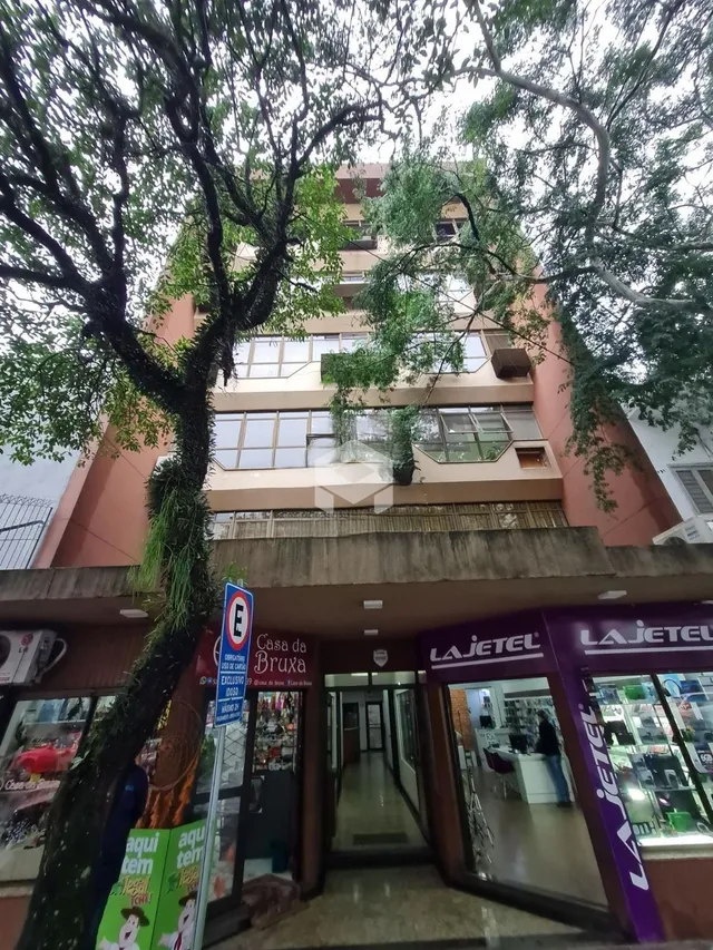 Fachada de um prédio residencial em Lajeado, Brasil, com árvores em primeiro plano.