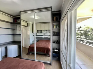 Quarto com armário de espelho e estantes em um imóvel em Lajeado.